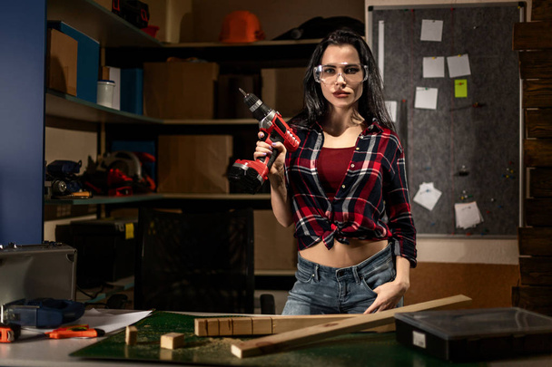 Woman with a drill screwdriver working in the workshop Studio alone - Фото, изображение