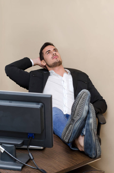 Lazy male worker relaxing and resting his feet on office desk, looking up - Foto, imagen