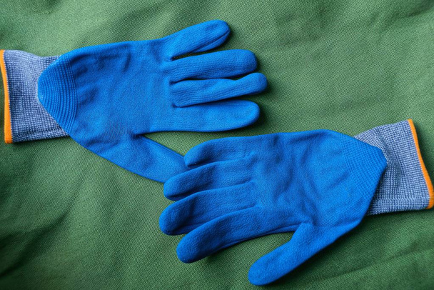 due guanti da lavoro blu posati su materia verde
 - Foto, immagini