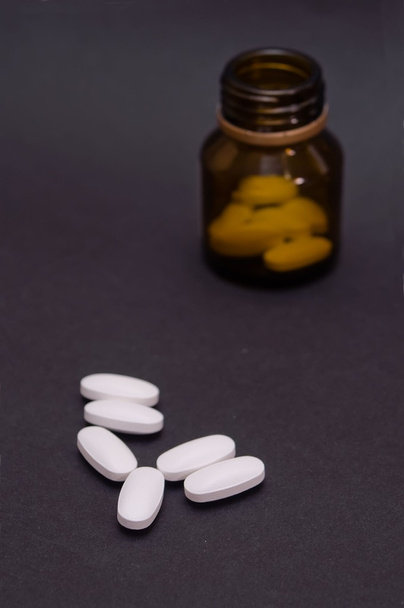 Medicine pills and a bottle on dark - Фото, изображение