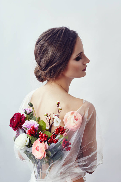 Woman with a bouquet of artificial flowers behind her. The girl  - Фото, изображение
