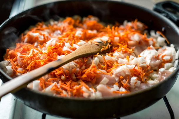 スープのための料理、刻んだニンジンと玉ねぎは鍋で揚げられています - 写真・画像