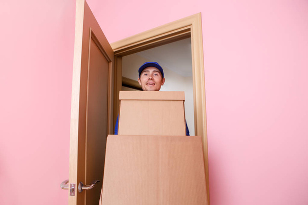 Image of courier man in blue t-shirt and baseball cap with cardboard boxes in hands. - Fotoğraf, Görsel