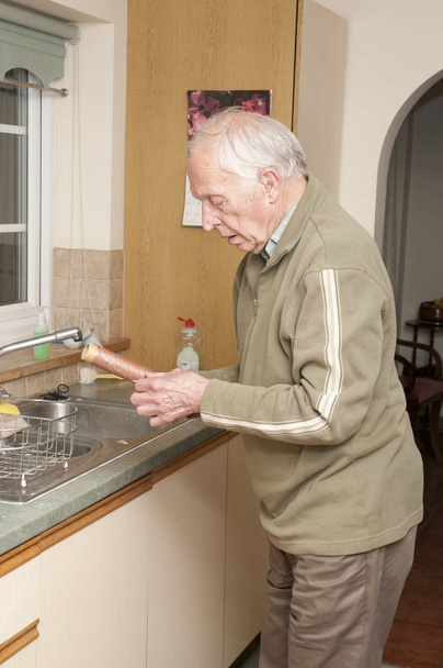 Elderly man with hearing aid working in kitchem - Φωτογραφία, εικόνα