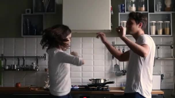 Happy teen couple dancing having fun in the kitchen - Záběry, video