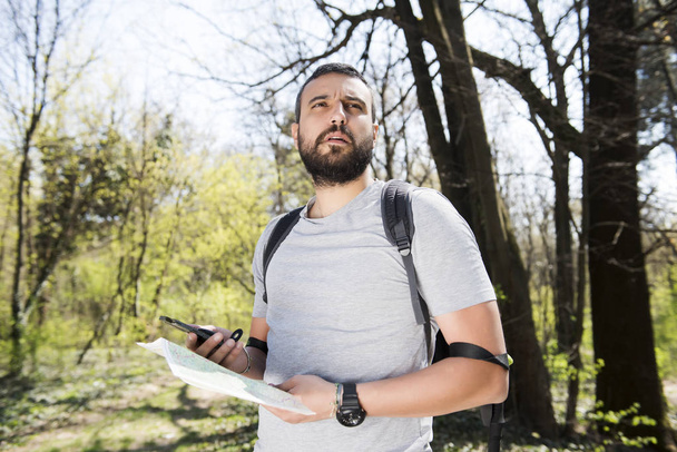 Male hiker using a map to locate the destination - Foto, afbeelding