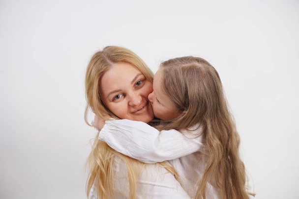 Real family of caucasian mother and daughter in white shirts in the studio background isolated - Photo, Image