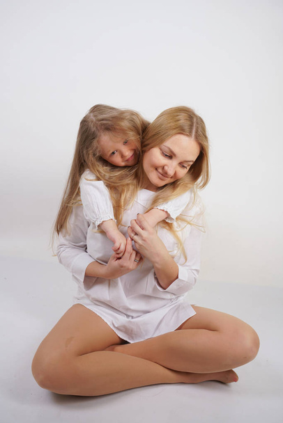 verdadeira família de mãe e filha caucasiana em camisas brancas no fundo do estúdio
 - Foto, Imagem