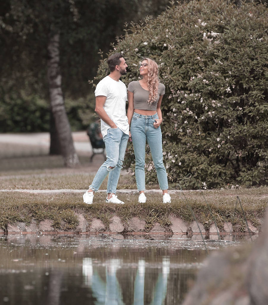 couple in love standing on the grass near the lake - Фото, изображение