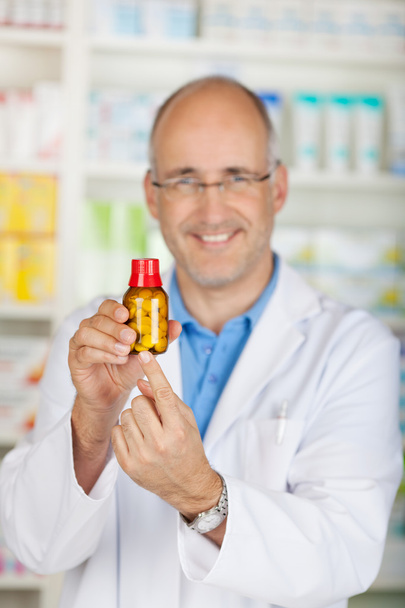 smiling pharmacist showing medicine bottle - Foto, Imagem
