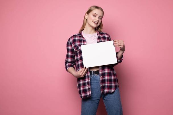 Щаслива усміхнена блондинка молода жінка в повсякденному одязі стоїть на рожевій стіні
 - Фото, зображення