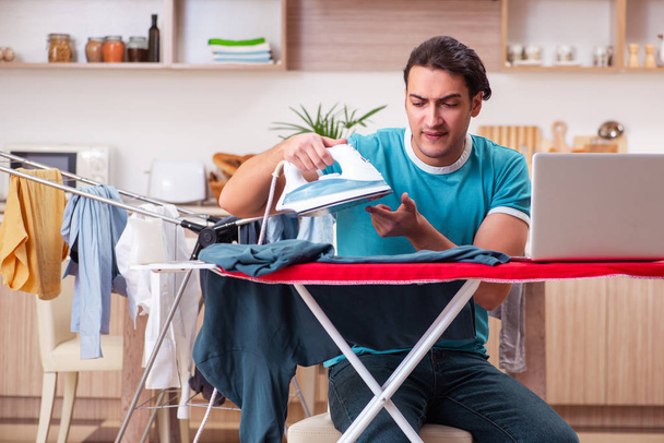 Young man husband doing clothing ironing at home  - Foto, imagen