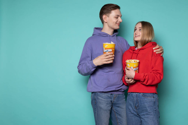 Photo of cute young couple in casual clothes with popcorn in hands - Photo, Image