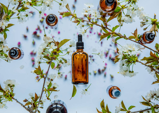 Чорні пляшки парфумів і вишневі квіти навколо
 - Фото, зображення
