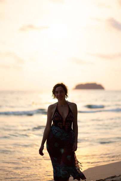 Beautiful woman in a colorful summer dress walking on the Thailand Ko Chang beach with beautiful white send during a sunset - Foto, afbeelding