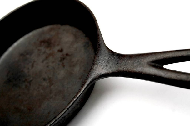 a black, well-seasoned cast iron frying pan on a white background - Foto, imagen