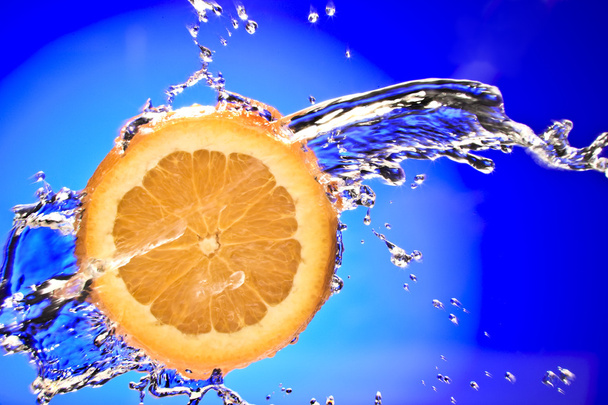 Close up view of sliced orange piece getting splashed with water - Photo, Image