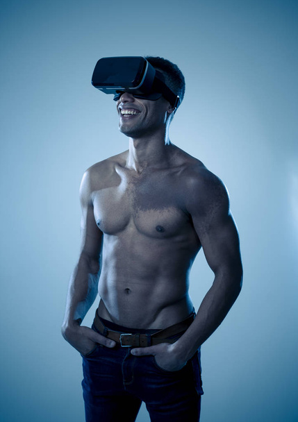 Attractive strong muscular african man using augmented VR glasses, feeling excited about simulation exploring new experiences. In virtual reality, virtual workout and new technology concept. - Fotografie, Obrázek