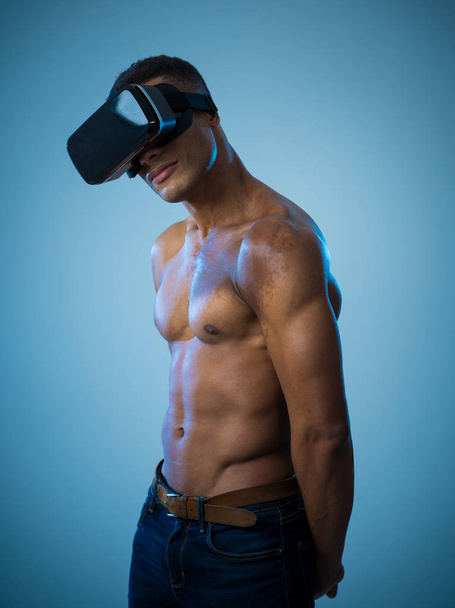 Attractive powerful african american man using augmented or VR goggles exploring new 3d world. Advertising of the power of virtual reality and augmented reality technology. 360 degree VR experiences. - Foto, afbeelding