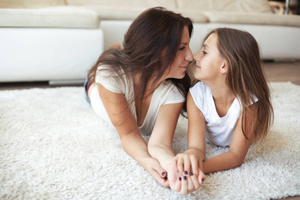 Mother with her preteen daughter having fun on a white carpet in living room at home - Foto, immagini