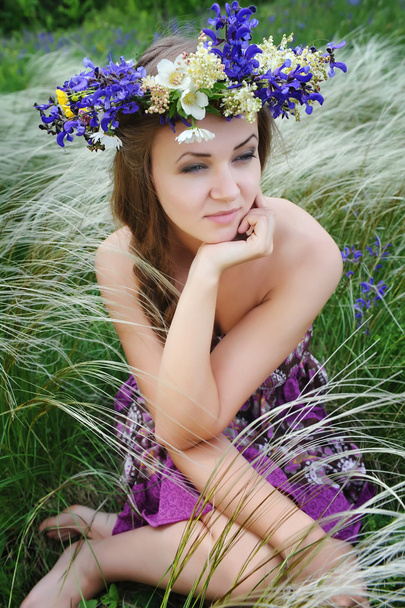 Beautiful young woman with flower wreath in the grass of feather - Photo, image