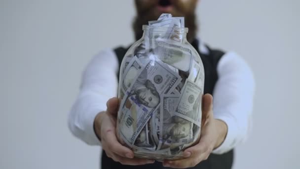 Bearded man holding a jar full of money isolated on white background. Getting rich. Clever storage of big money. Savings concept.Business man, millionaire, billionaire, bearded man with many banknote. - Footage, Video