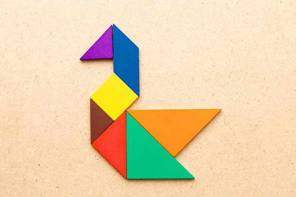 Puzzle couleur tangram en forme de cygne sur fond bois
 - Photo, image