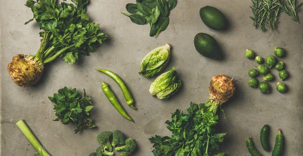 Healthy vegan salad ingredients layout. Flat-lay of green vegetables and herbs over grey concrete background, top view, wide composition. Vegetarian, clean eating, raw, Spring light food concept - Фото, изображение