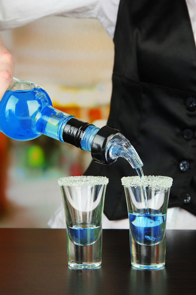 Barmen mano con botella verter bebida en vasos, sobre fondo brillante
 - Foto, Imagen