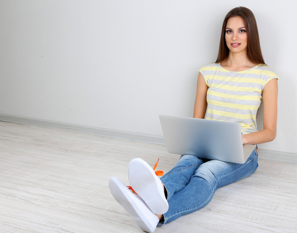 Beautiful young woman sitting with laptop in room - Φωτογραφία, εικόνα