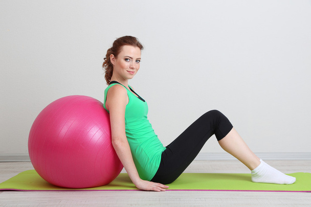 Portrait of beautiful young woman exercises with gym ball - Фото, зображення