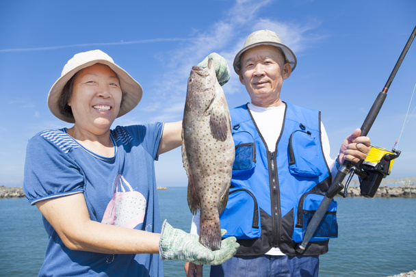 szczęśliwa para starszy połowów i pokazuje duże grouper - Zdjęcie, obraz
