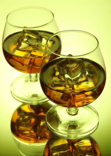 Brandy glasses with ice on green background - Fotografie, Obrázek