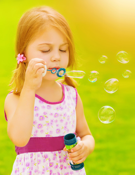 Baby girl blowing soap bubbles - Foto, afbeelding