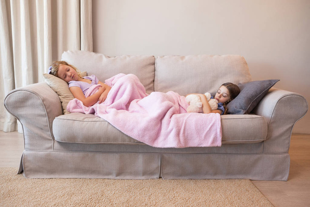 View of two young girls sleeping on couch at home - Foto, Imagem