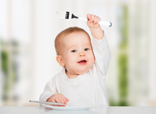 Funny baby with a knife and fork eating food - Photo, Image