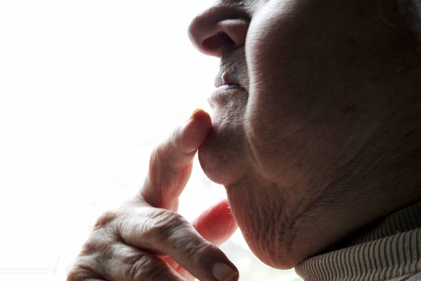 Finger resting on chin of an elderly lady - Foto, immagini