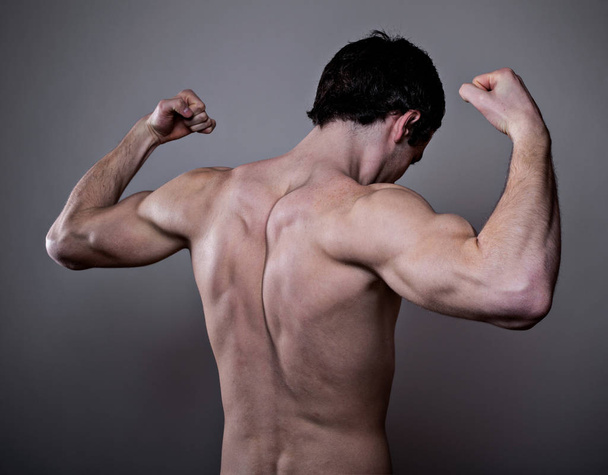 Muscular male back over dark background - Foto, afbeelding