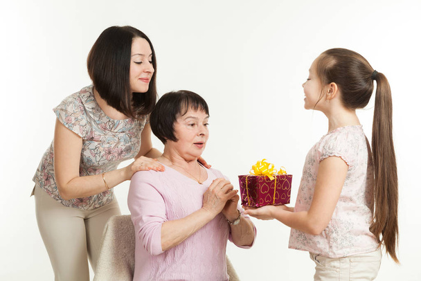 the daughter and the granddaughter give a gift to the grandmother - Foto, immagini