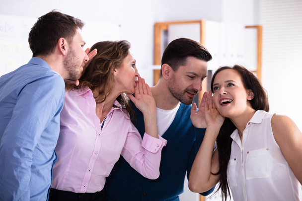 Business Colleague Whispering Secret Gossip To An Amazed Shocked Woman With Wide Open Mouth - Фото, изображение