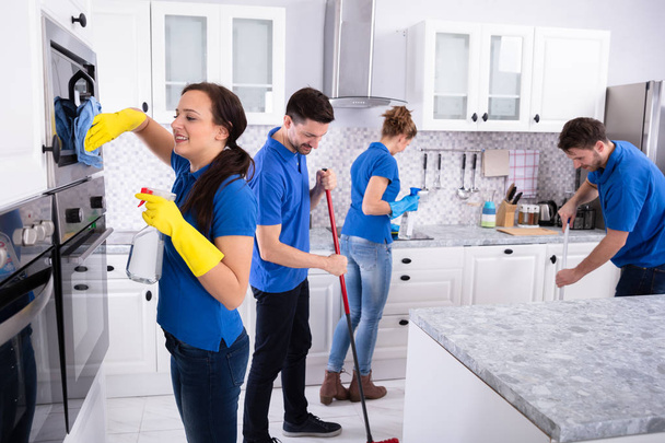 Group Of Young Janitors In Uniform Cleaning Kitchen At Home - Photo, Image
