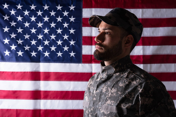 Zbliżenie męskiego żołnierza stojącego przed flagą Nas - Zdjęcie, obraz