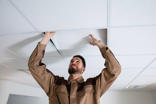 Close-up Of Young Electrician Repairing Ceiling In Office - Фото, изображение