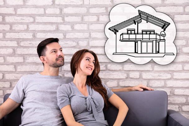 Happy Couple Dreaming Of Having Future Home While Sitting On Sofa - Photo, image