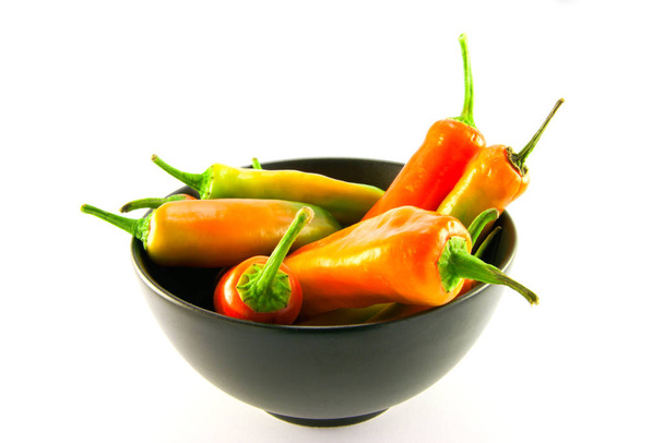 Mixed red and green chillis in a black bowl with clipping path on a white background - Fotoğraf, Görsel