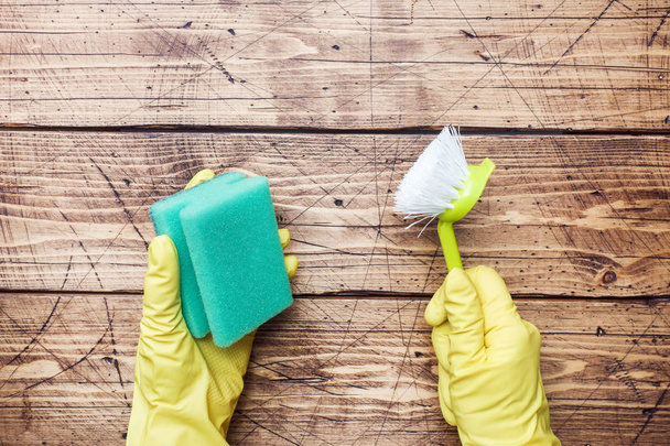 Hand in yellow glove and cleaning sponge for cleaning on wooden background. Home cleaning concept. Top view, copy space - Φωτογραφία, εικόνα