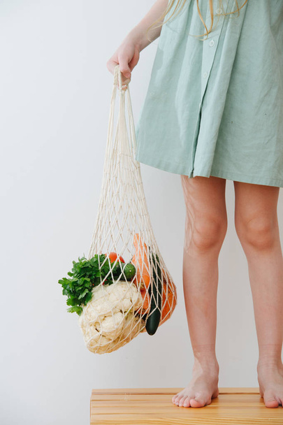 Little gir holding shopping bag with vegetables. - Φωτογραφία, εικόνα