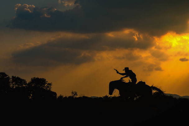 silhueta de vaqueiro em um cavalo durante o pôr do sol agradável
 - Foto, Imagem