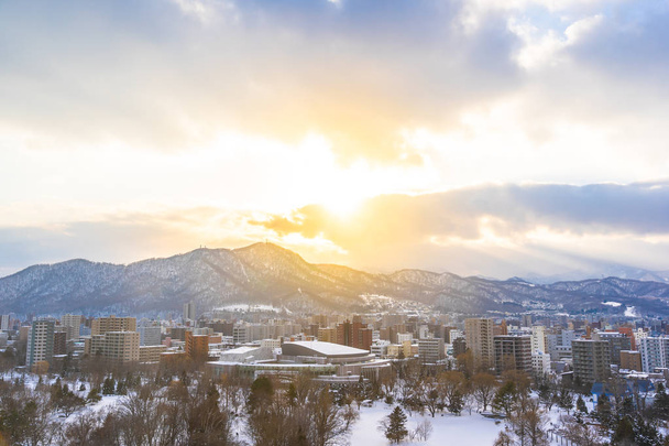 Edifício de arquitetura bonita com paisagem de montanha na temporada de inverno na hora do pôr do sol Sapporo cidade Hokkaido Japão
 - Foto, Imagem