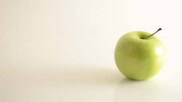 Rotating Granny Smith Apple On Acrylic Against White - Crane Down - Footage, Video